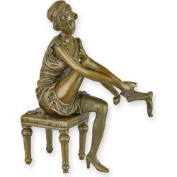 A BRONZE SCULPTURE OF A WOMAN PUTTING ON HER SOCKS