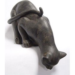 A RESIN FIGURINE OF A CAT LOOKING DOWN